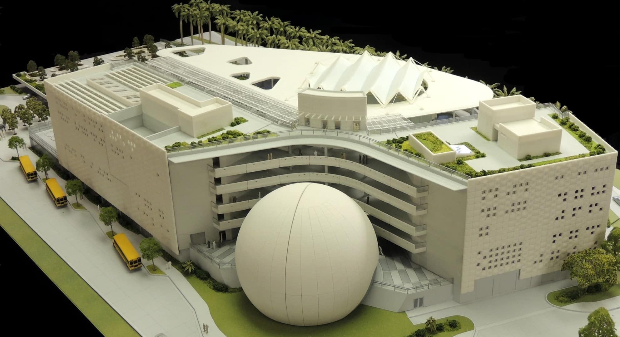 3D Printed Model of Building - Grimshaw A detailed model of a modern architectural building with a large spherical structure in front, rooftop gardens, and surrounding trees. Several yellow buses are parked on the side, showcasing how large format printing can enhance urban planning visuals.