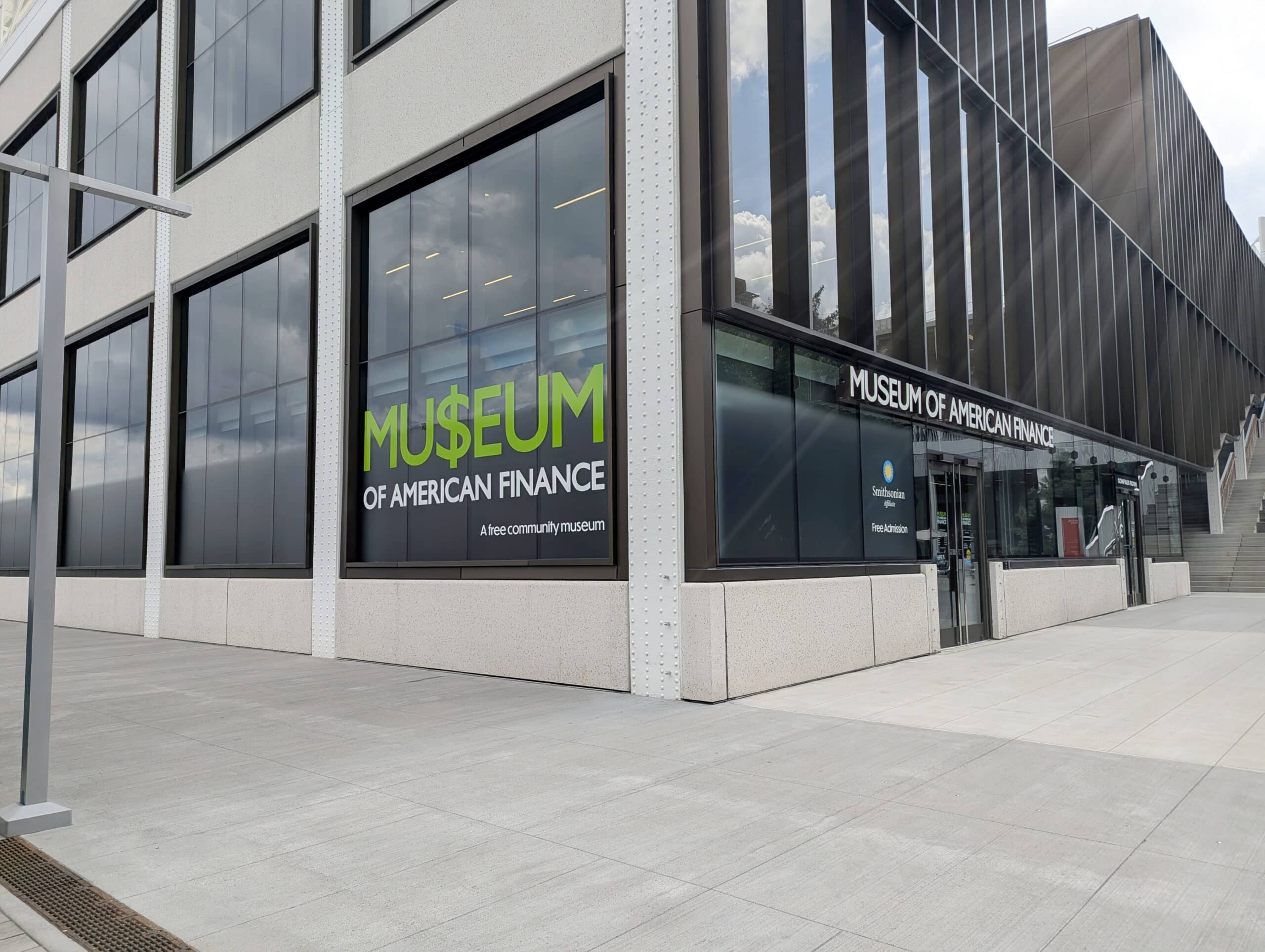 Exterior view of the Museum of American Finance, showing large windows, building facade, and the museum entrance on a city sidewalk.