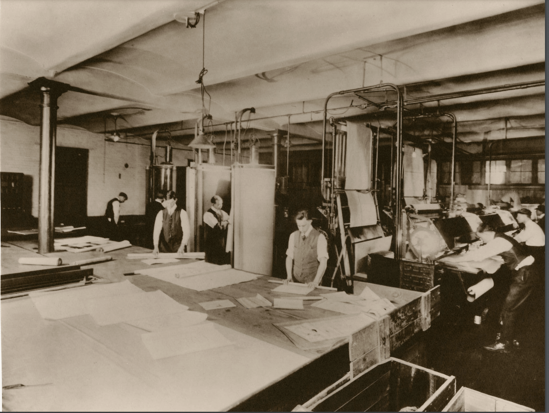 A sepia-toned photograph of a busy print shop bustling with workers operating machinery and providing managed print services while efficiently handling paper.