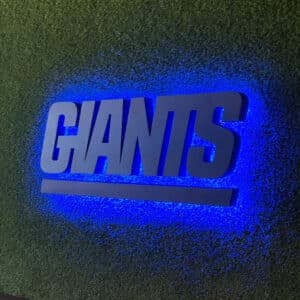 A sign with the word "GIANTS" in bold letters is displayed on a textured green wall, illuminated by blue backlighting.