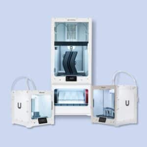 Four Ultimaker 3D printers are displayed against a light blue background, including two smaller models, one medium-sized, and one large printer with a multi-spool filament system.